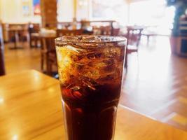 cola glas met ijs op houten tafel in restaurant achtergrond foto