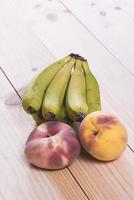 fruit op houten tafel. bananen, perziken en paraguayanen