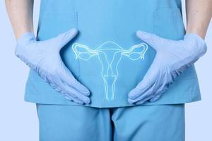 arts gynaecoloog in een medisch uniform en een model van het voortplantingssysteem van een vrouw, de baarmoeder, ter hoogte van de bekkenbeenderen van een vrouw. gezondheidsconcept voor vrouwen. foto