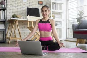 fit jonge vrouw die thuis yoga beoefent via online les met professionele instructeur, sport en gezond levensstijlconcept. foto