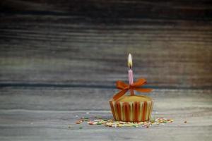 gelukkige verjaardag cupcake en boog kaars op tafel op houten achtergrond met kopie ruimte. schattig eten gelukkige verjaardag achtergrond concept foto