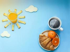 creatief ontbijtidee, zonsopgangochtend blauwe lucht met wolkenmaaltijd, jus d'orange, knapperige broodbotersuiker, troebel witbrood, croissant, hete zwarte koffie en sinaasappelfruit. wakker worden op een heldere dag foto