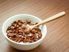 Graanchocoladesmaak met lepel en melk in een kom op houten tafel, ontbijt klaar om 's ochtends te eten foto