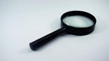 close-up shot van een zwart vergrootglas op een witte achtergrond. foto