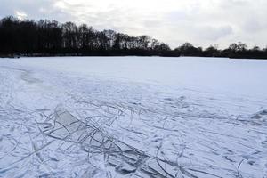 uitzicht op een bevroren meer in de winter met veel schaatsbanen. foto