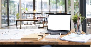 laptop of notebook met leeg scherm op houten tafel in onscherpe achtergrond met huis of kantoor modern, natuur oranje bokeh en zonlicht in de ochtend. foto