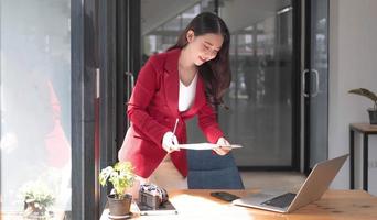 portret van jonge aziatische vrouw hand freelancer werkt haar baan op computer tablet in moderne kantoren. doen van boekhoudkundige analyse rapport vastgoedinvesteringsgegevens, financiële en fiscale systemen concept. foto