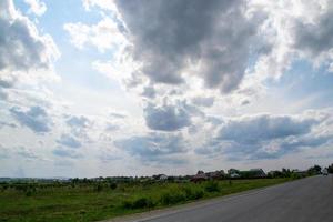 een weg met een bos achtergrond en een blauwe lucht met wolken. foto