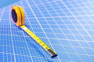 3d illustratie van een geel meetlint op een achtergrond van blauw millimeterpapier. handmeetinstrument voor bouw-, renovatie- of timmerwerk. foto