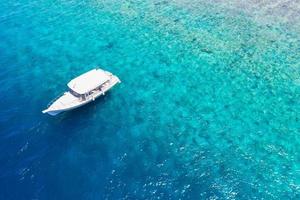 prachtige turquoise oceaanwater en boot, bekijk luchtfoto drone zeegezicht. tropische zeegolven, geweldig luchtkoraalrif, lagune. mensen recreatieve buitenactiviteiten, zwemmen, snorkelen, duiktoerisme foto