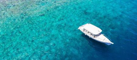 luxe klein jacht verankerd in ondiep water, oceaan lagune koraalrif in maldiven. snorkel duikboot, buitenactiviteit, zomerrecreatie foto