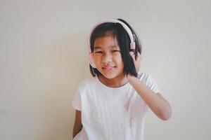 portret van jonge gelukkig Aziatisch meisje genieten van muziek met koptelefoon op witte achtergrond. geniet van het geluidsconcept. foto