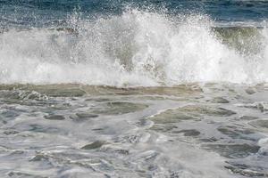 golf slaat tegen de rotsen van een kust foto