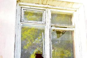 het raam in het huis is van gebroken glas vandalisme. foto