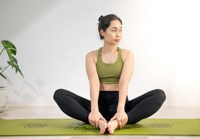 vrouw die yoga doet op de groene yogamat om thuis te mediteren en te oefenen. foto