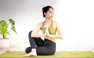 vrouw die yoga doet op de groene yogamat om thuis te mediteren en te oefenen. foto