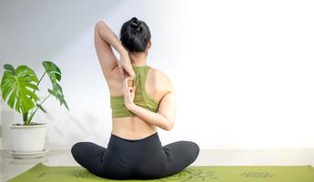 vrouw die yoga doet op de groene yogamat om thuis te mediteren en te oefenen. foto