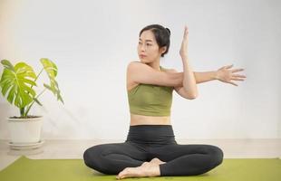 vrouw die yoga doet op de groene yogamat om thuis te mediteren en te oefenen. foto