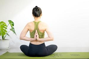 vrouw die yoga doet op de groene yogamat om thuis te mediteren en te oefenen. foto