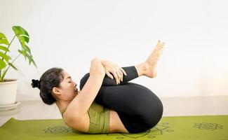 vrouw die yoga doet op de groene yogamat om thuis te mediteren en te oefenen. foto