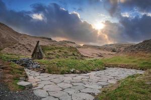 mooi turfhuis en geothermische hete lente in hrunalaug tegen bewolkte hemel foto