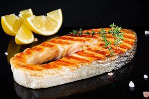 gegrilde zalm vis op stenen bord. Salt atlantic zalm gebakken op grill met citroen foto