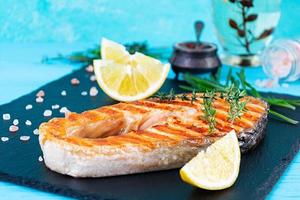 gegrilde zalm vis op stenen bord. Salt atlantic zalm gebakken op grill met citroen foto