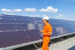 het zonnepark, zonnepaneel met ingenieurs lopen om de werking van het systeem te controleren, alternatieve energie om 's werelds energie te besparen, fotovoltaïsche module-idee voor de productie van schone energie foto