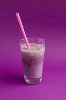 glas bessen smoothie met stro op paarse achtergrond. roze milkshake. gezond drankje. bosbessencocktail foto