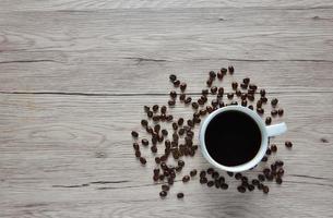 zwarte koffiemokken en koffiebonen op een houten tafel. foto