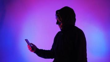 anonieme hacker en gezichtsmasker met smartphone in de hand. foto