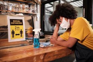 afro-amerikaanse vrouwelijke café-barista met beschermend gezichtsmasker wachtend op klanten in een coffeeshop, klein bedrijf in nieuwe normale levensstijl, economische impact van covid19 pandemische quarantaine. foto