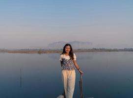 glimlach gelukkige aziatische vrouw toerist ontspant zich met een prachtig kalm berglandschap met reflectie aan de voorkant van het meer in de ochtend met mistige lucht foto