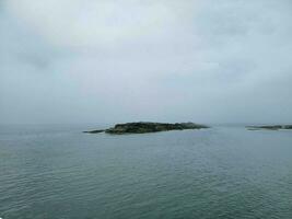 rotsachtig eiland en water en vogels en wolken in Maine foto