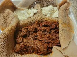 Ethiopisch eten kitfo rauw rundvlees met injera brood en kaas foto
