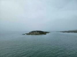 rotsachtig eiland en water en vogels en wolken in Maine foto