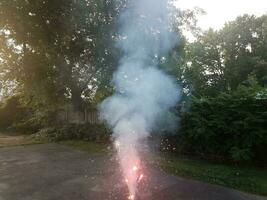 aangestoken kleurrijk vuurwerk op asfaltoprit met rook foto