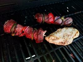 beef kebob met uien en paprika op een stokje op een grill met kip foto