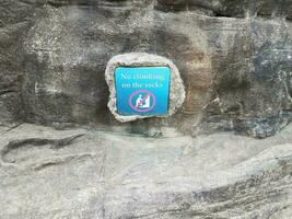 blauw bord met geen klimmen op de rotsen met grijze rots foto