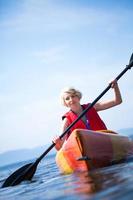 vrouw met veiligheidsvest kajakken alleen op een kalme zee