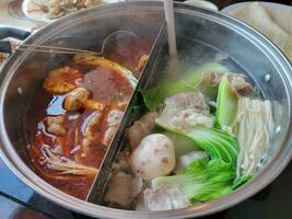 chinese hot pot met pittige en gewone bouillon en vlees en groenten foto