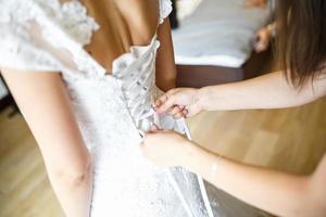 bruidsmeisje trekt bruid trouwjurk recht foto