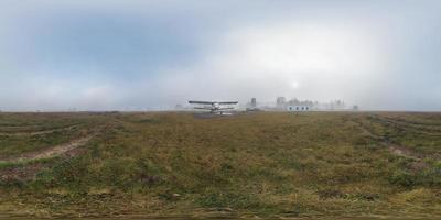 mistige zonsopgang op weide met oud vliegtuig. volledig 360 rechthoekig panorama. skybox in virtual reality of 3D-graphics content als fotorealistische achtergrond. foto