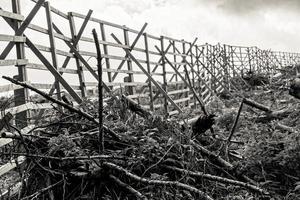 grijswaarden van een oude houten omheining in een landelijk gebied op bewolkte hemelachtergrond foto