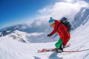 skiër skiën bergaf in het hooggebergte tegen zonsondergang foto