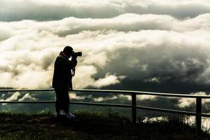 zwarte silhouetfotograaf met mist met berg, zee van mis foto