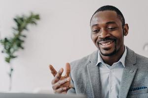 lachende Afro-Amerikaanse zakenman die een videogesprek houdt met klanten op laptop, adviseert klanten foto