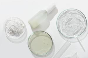 bovenaanzicht van cosmetisch product in glazen fles en petrischaal met medium en reageerbuis op een laboratoriumtafel. laboratoriumonderzoek naar cosmetische ingrediënten voor huidverzorging en productveiligheid foto