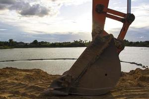 graafmachines staan 's avonds na het werk stil en gebruiken de armen van de auto als frame om 's avonds de prachtige lucht en wolken in verschillende kleuren te zien, een lichtstraal in de prachtige rivier foto