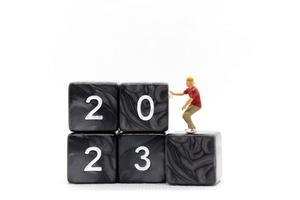miniatuur mensen graffitikunstenaar die nummer 2023 op blok spuit foto